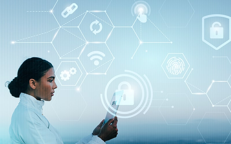 A white clad female scientist is focusing on cybersecurity while typing on a tablet.